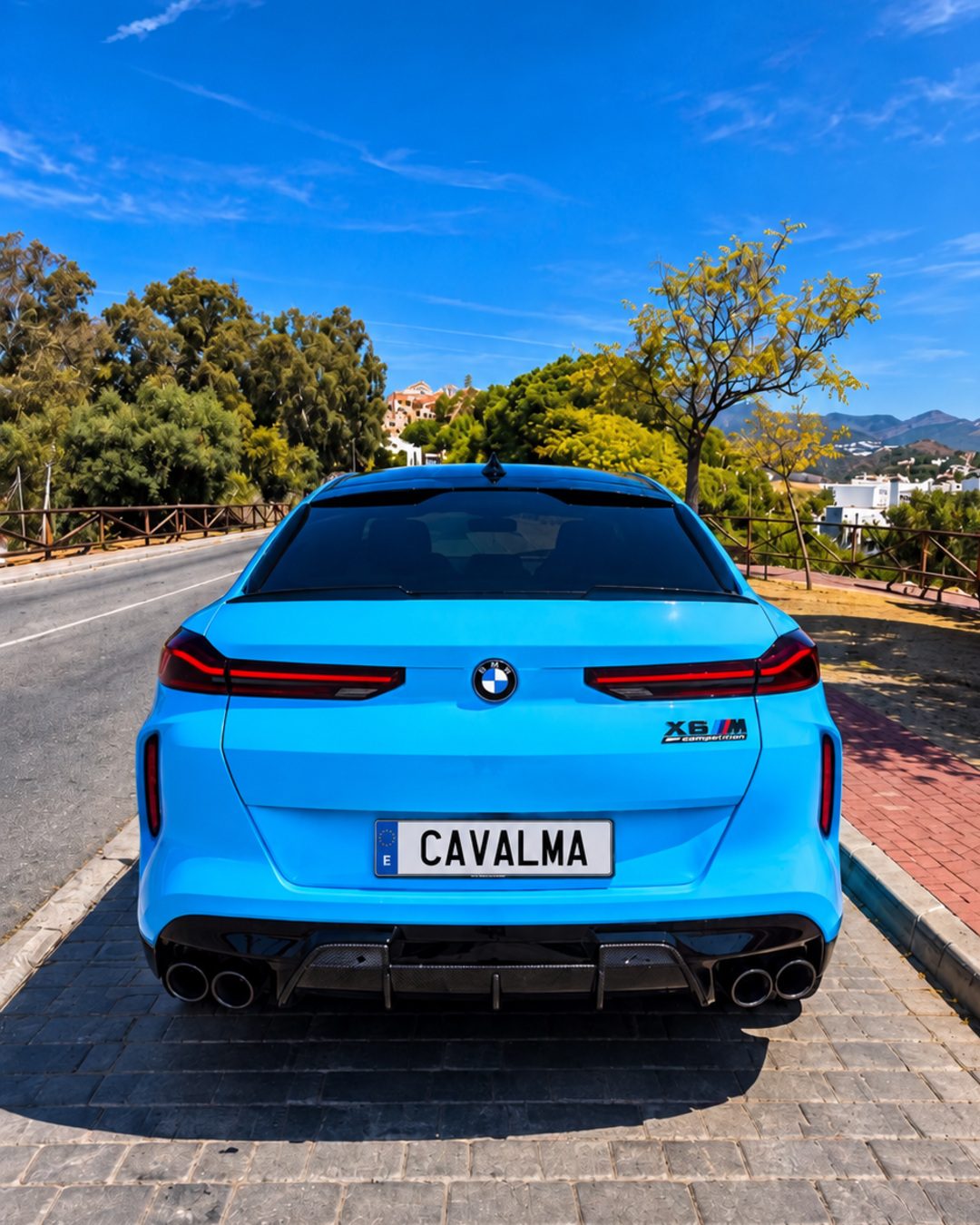 Синий BMW X6 M, вид сзади с рельефной крышкой багажника, задней оптикой, четырьмя выхлопными патрубками и чёрным задним диффузором.