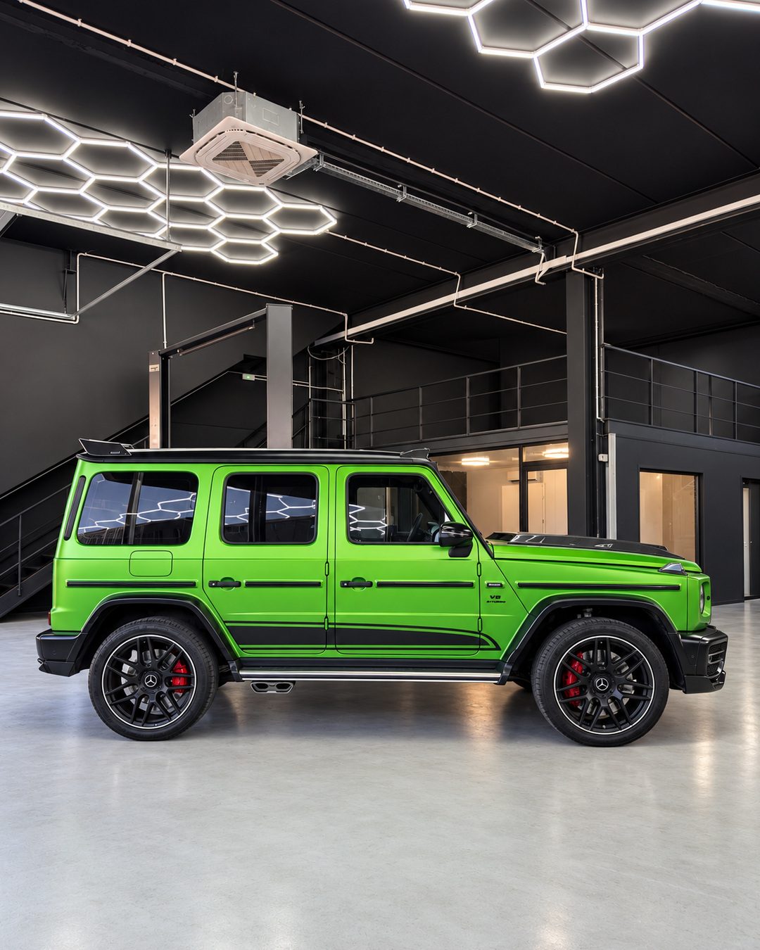 Mercedes-Benz G63 - Side profile of the green Mercedes-Benz G63 showing its box-shaped body, black exterior trim, large wheels and red brake calipers.