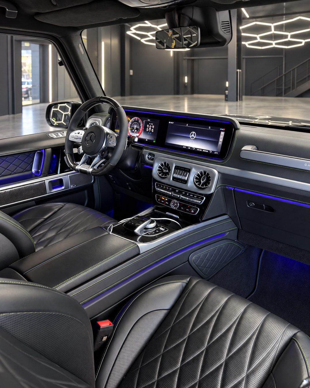 Mercedes-Benz G63 - Mercedes-Benz G63 front cabin with a black leather interior, digital dashboard, centre console and blue ambient lighting.