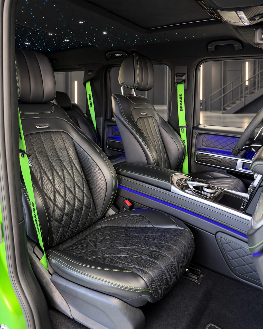 Mercedes-Benz G63 - Front black leather seats of the Mercedes-Benz G63 showing diamond-pattern upholstery, green seat belts and the centre console.
