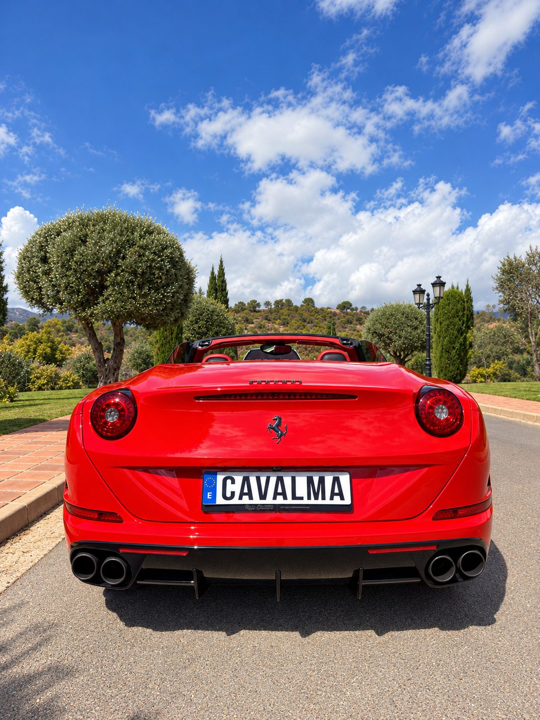 Вид сзади на красный Ferrari California T с открытой крышей: эмблема Ferrari, задний диффузор и номер CAVALMA.