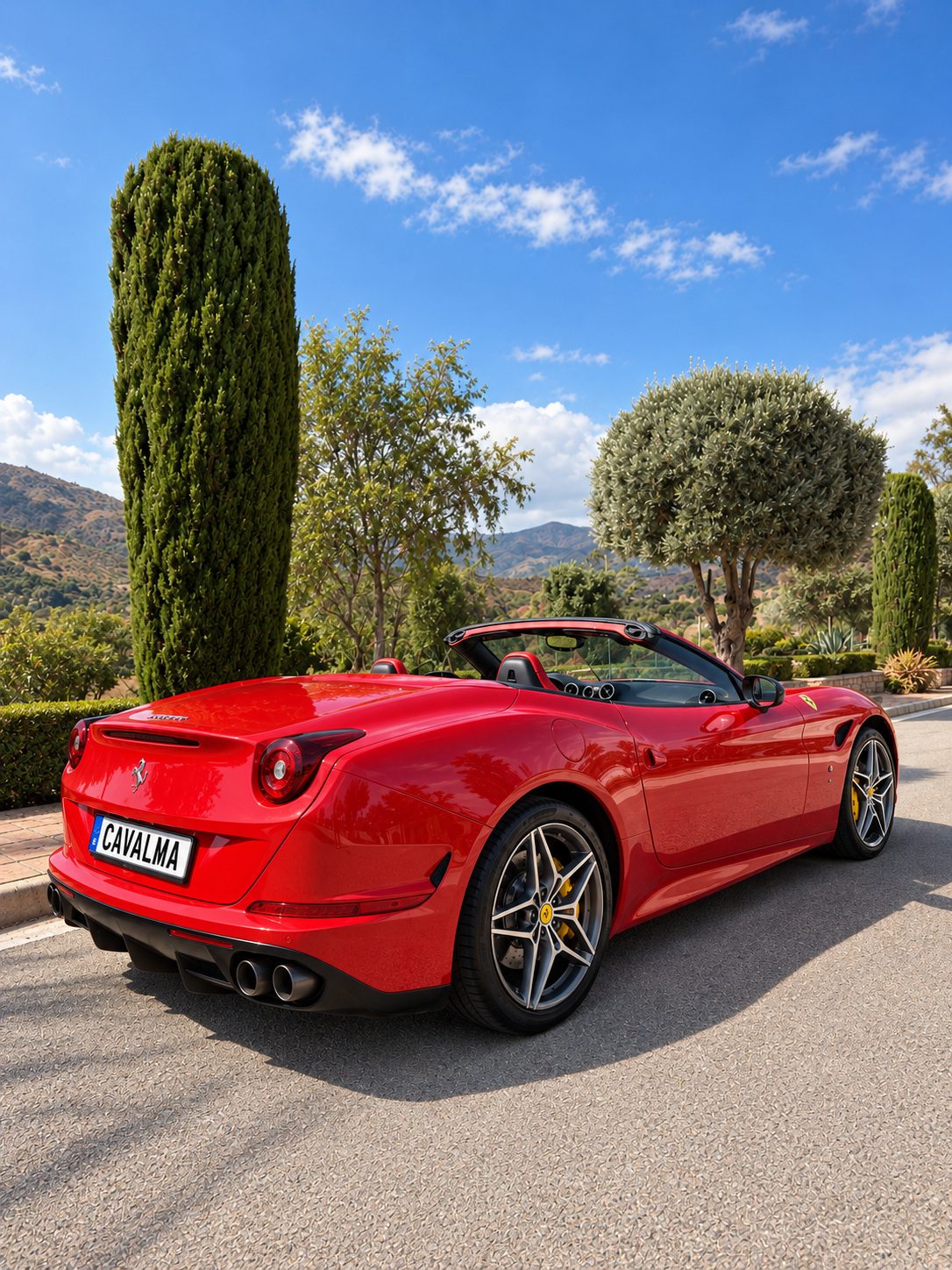 Ferrari California T - Rear three-quarter view of the red Ferrari California T with the roof open, showing its convertible silhouette, rear wheels and twin exhausts.