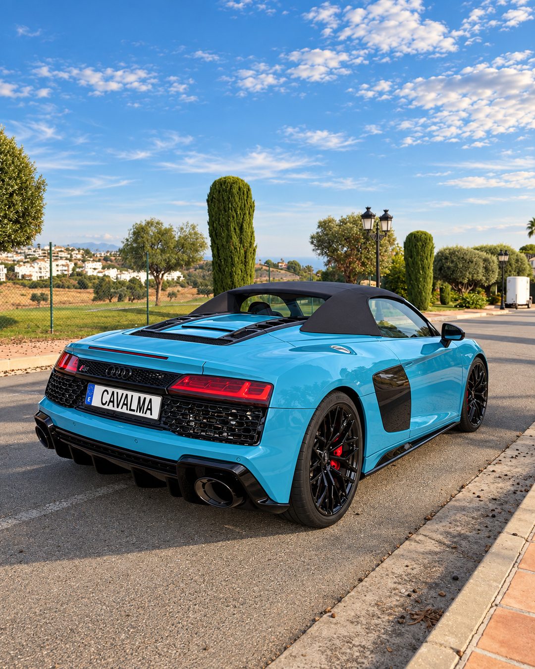 Rear three-quarter view of a blue Audi R8 Spyder rental in Marbella with black soft top, sports exhaust and CAVALMA plate.