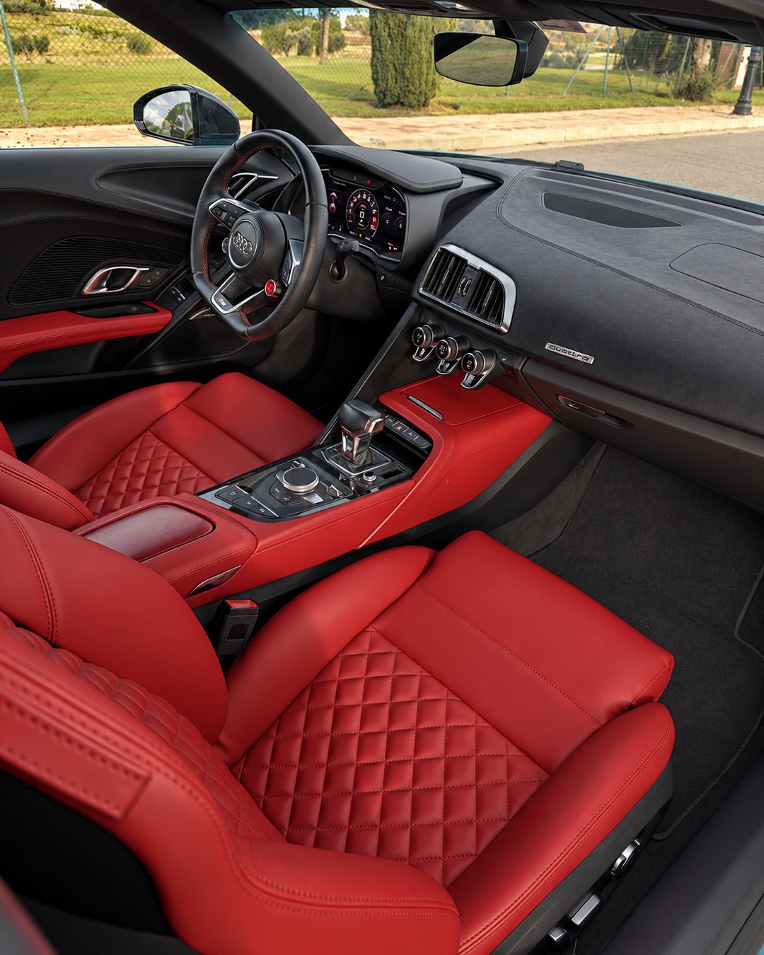 Audi R8 Spyder cockpit with red leather interior, digital driver display and performance-focused centre console.