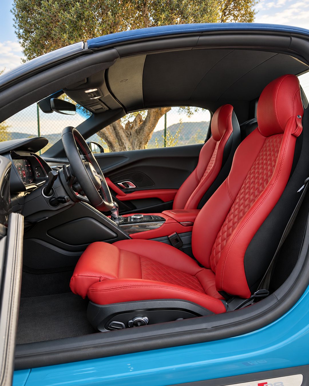 Audi R8 Spyder red leather sports seats with diamond stitching and driver-focused two-seat interior.