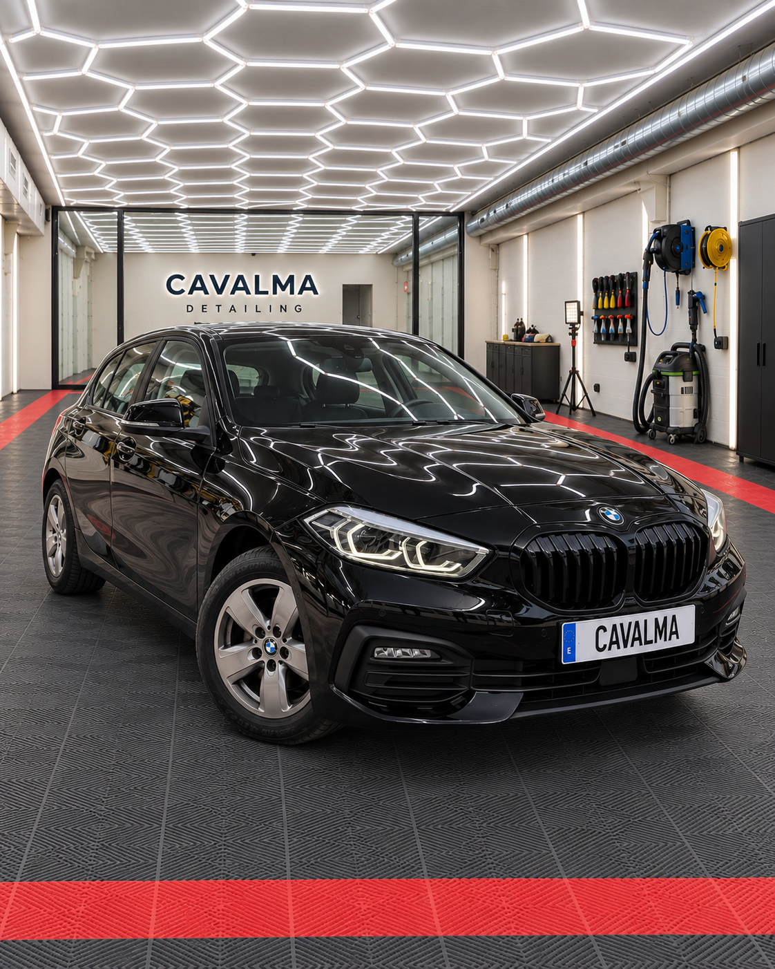 Black BMW 1 Series hatchback photographed from the front three-quarter angle inside a CAVALMA detailing facility, showing its BMW grille, headlights and alloy wheels.