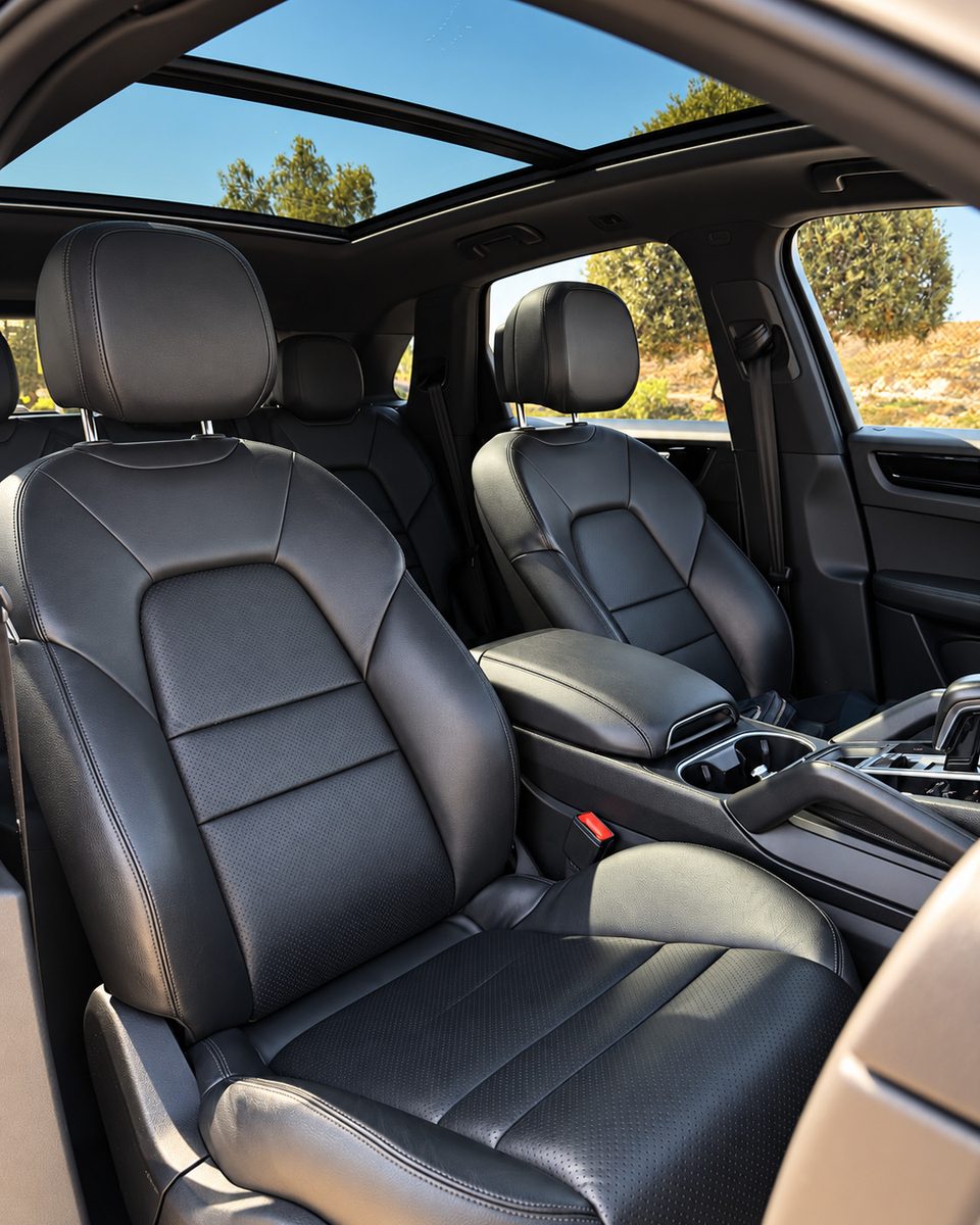 Porsche Cayenne black front seats and centre console beneath the panoramic glass roof.